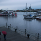 People walk under the rain near boats docked off downtown Victoria, British Columbia, on January 21, 2020.